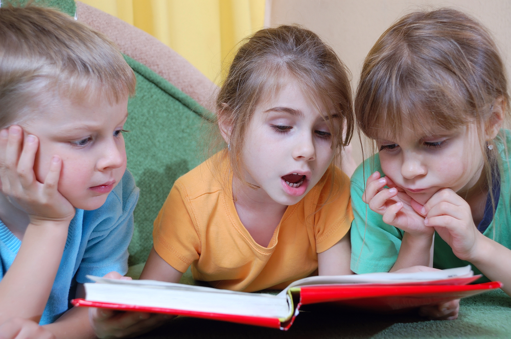 three kids reading the same book